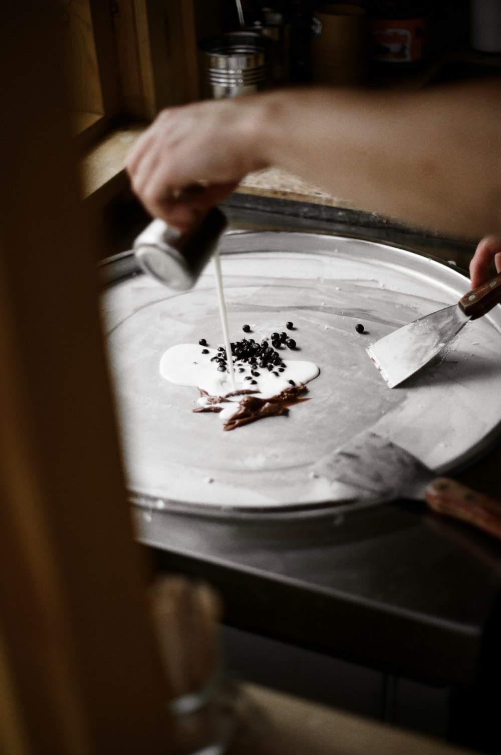 person pouring liquid on pan with spices