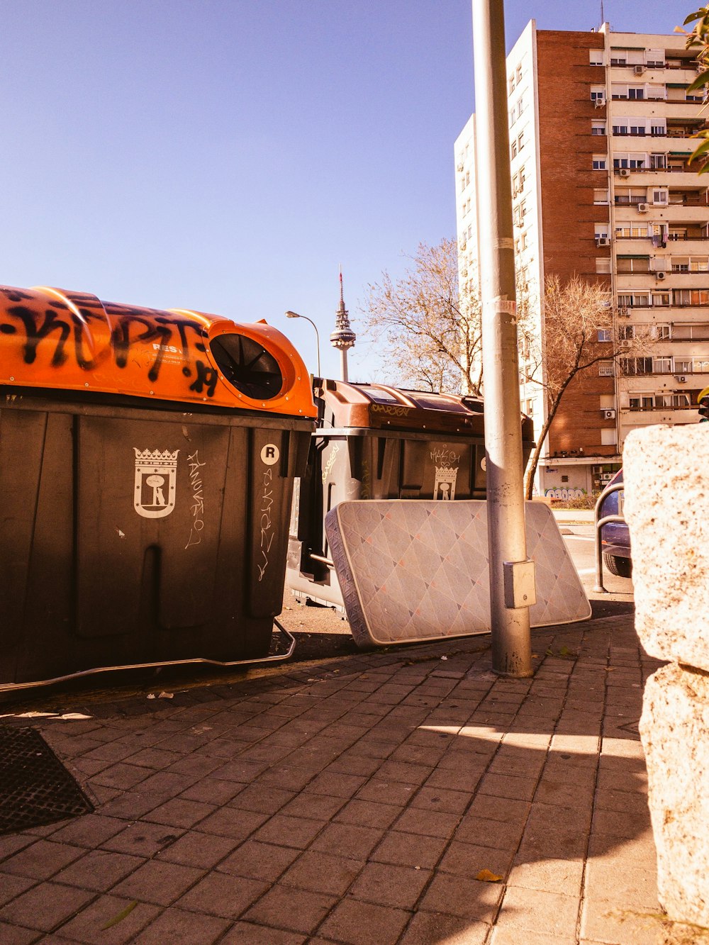 white mattress leaned near dumpster