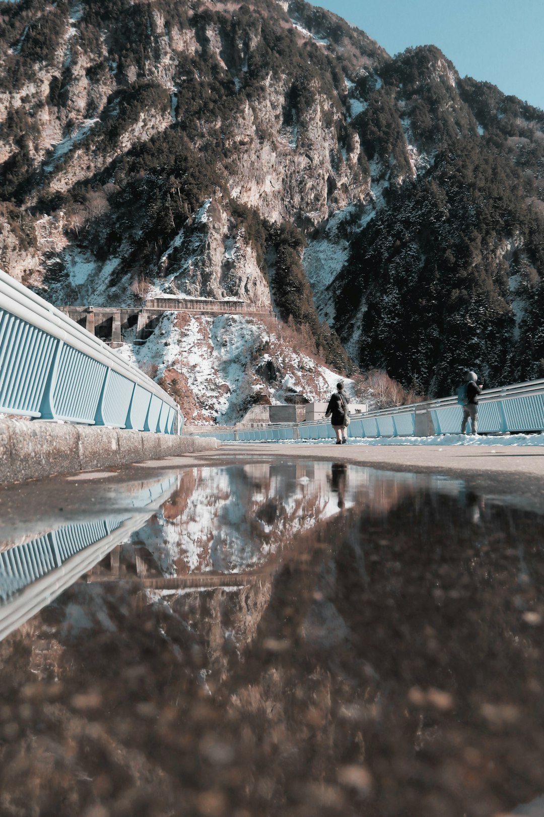 people walking on boardwalk near mountain at daytime