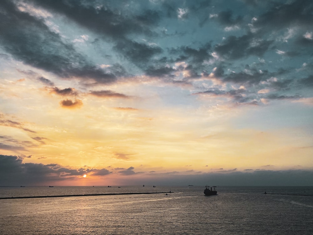 boat on body of water under blue, gray, and yellow sky