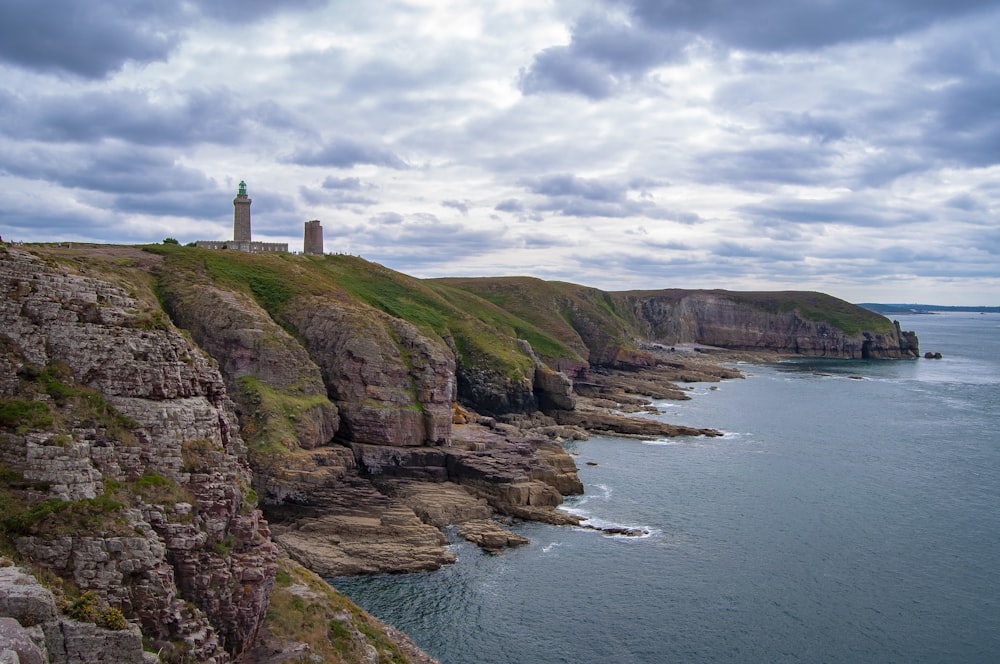 building on cliff facing ocean under cloudy sky