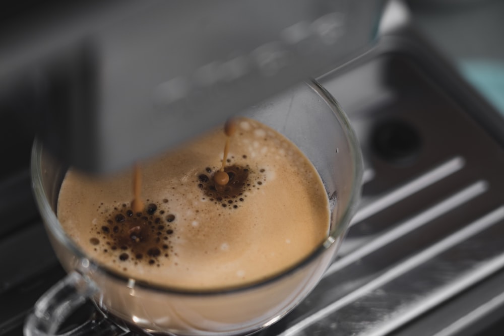 caffè gocciolante su tazza di vetro trasparente