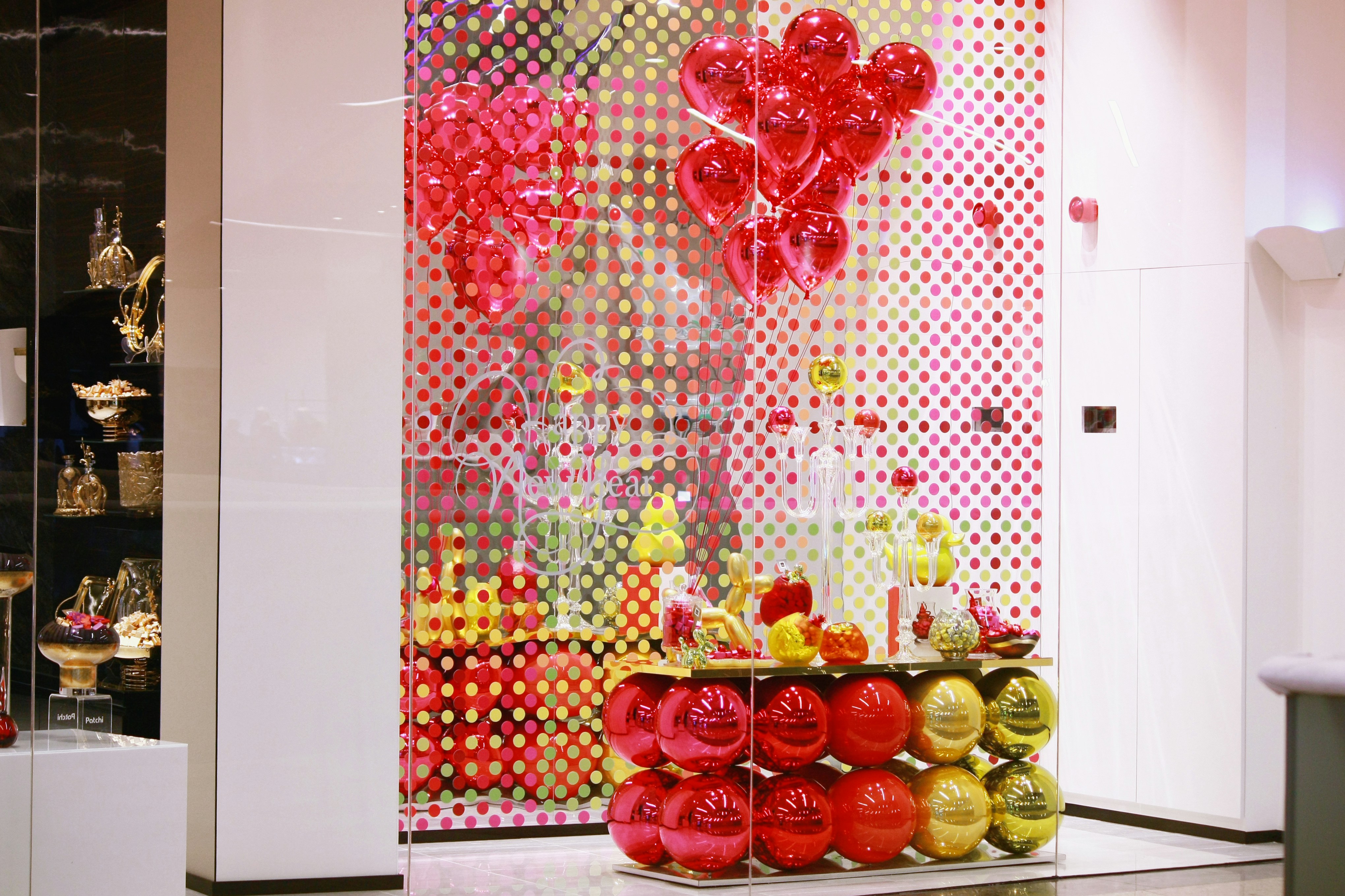 Storefront display decorated with red balloons and festive ornaments.