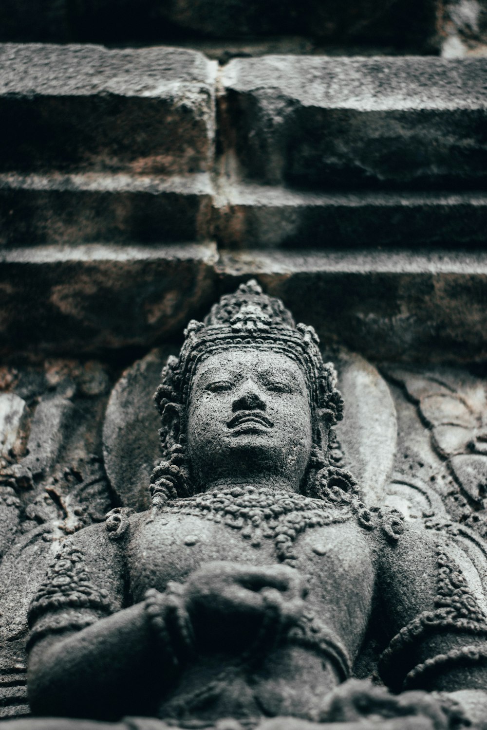 Une statue de Bouddha devant un mur de briques