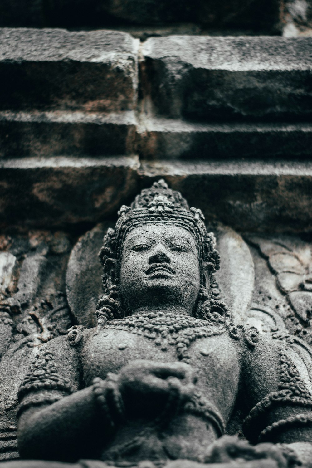 a statue of a buddha in front of a brick wall