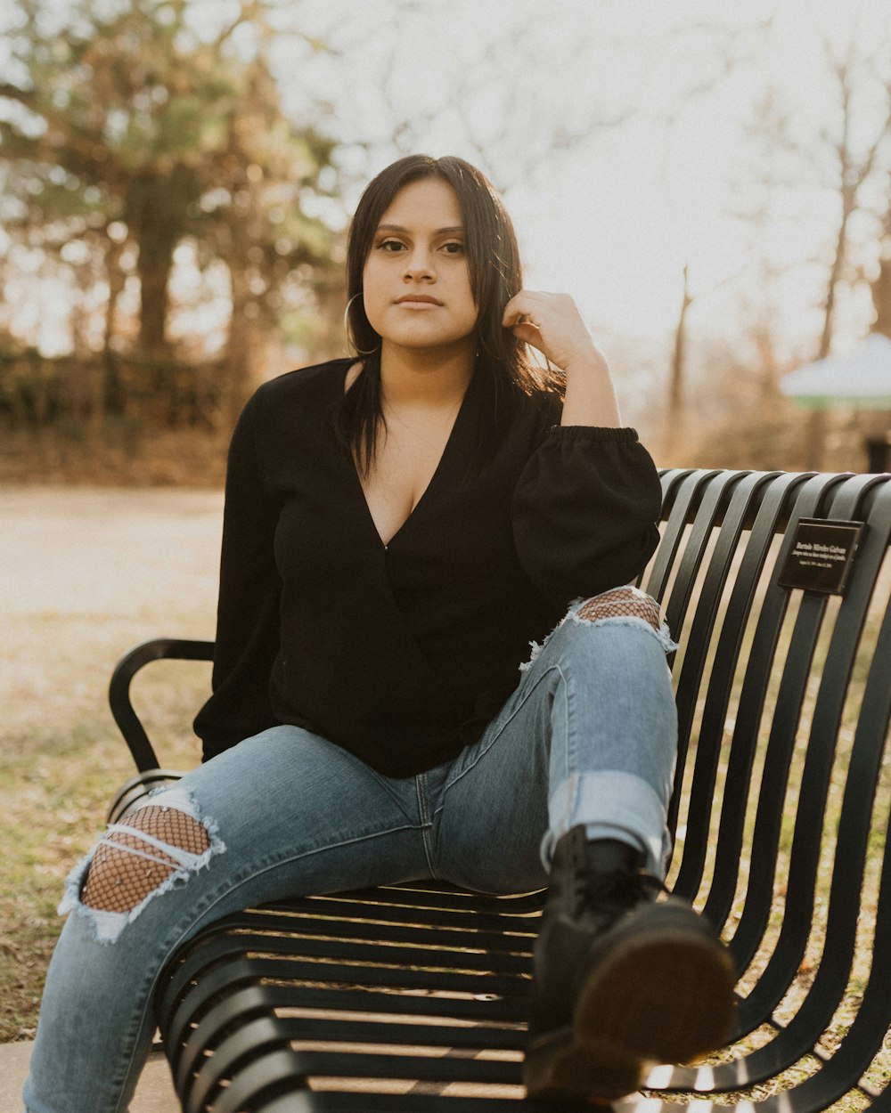 woman wearing black shirt sitting on metal bench during daytime