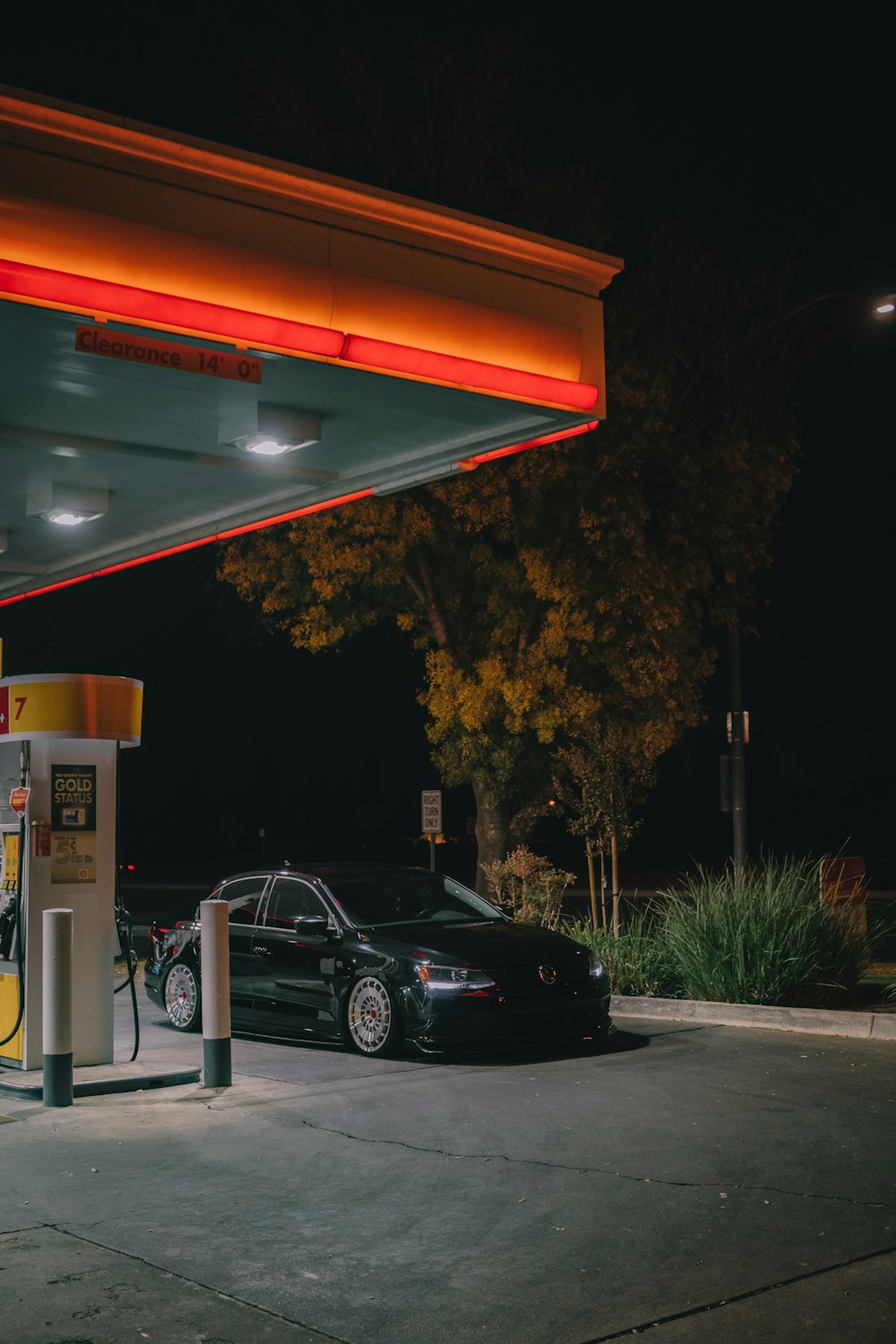 black sedan park on gasoline station during nighttime