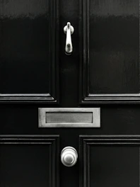 Technician carefully installing a matte black Stilex steel security door in a modern home entrance.
