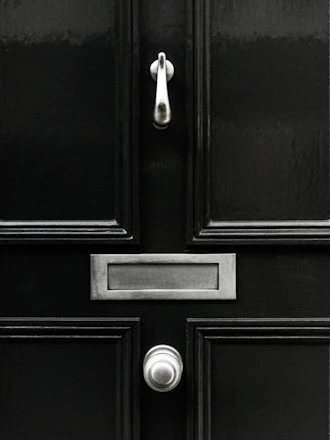 Technician carefully installing a matte black Stilex steel security door in a modern home entrance.
