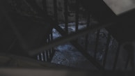 A dark and moody staircase with metal bars casting shadows. The dim lighting and shadowy elements suggest a mysterious or neglected atmosphere. The floor and walls appear worn and textured, enhancing the eerie feeling.