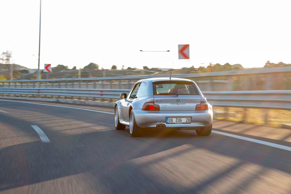 silver coupe travelling on road