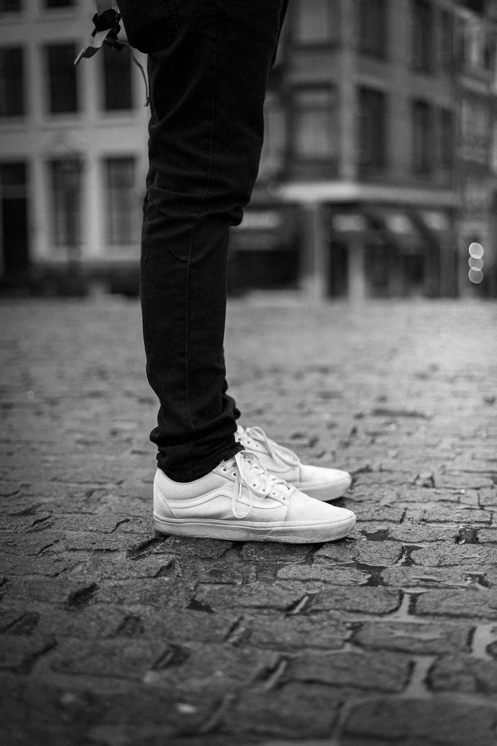 grayscale photography of standing person wearing low-top sneakers