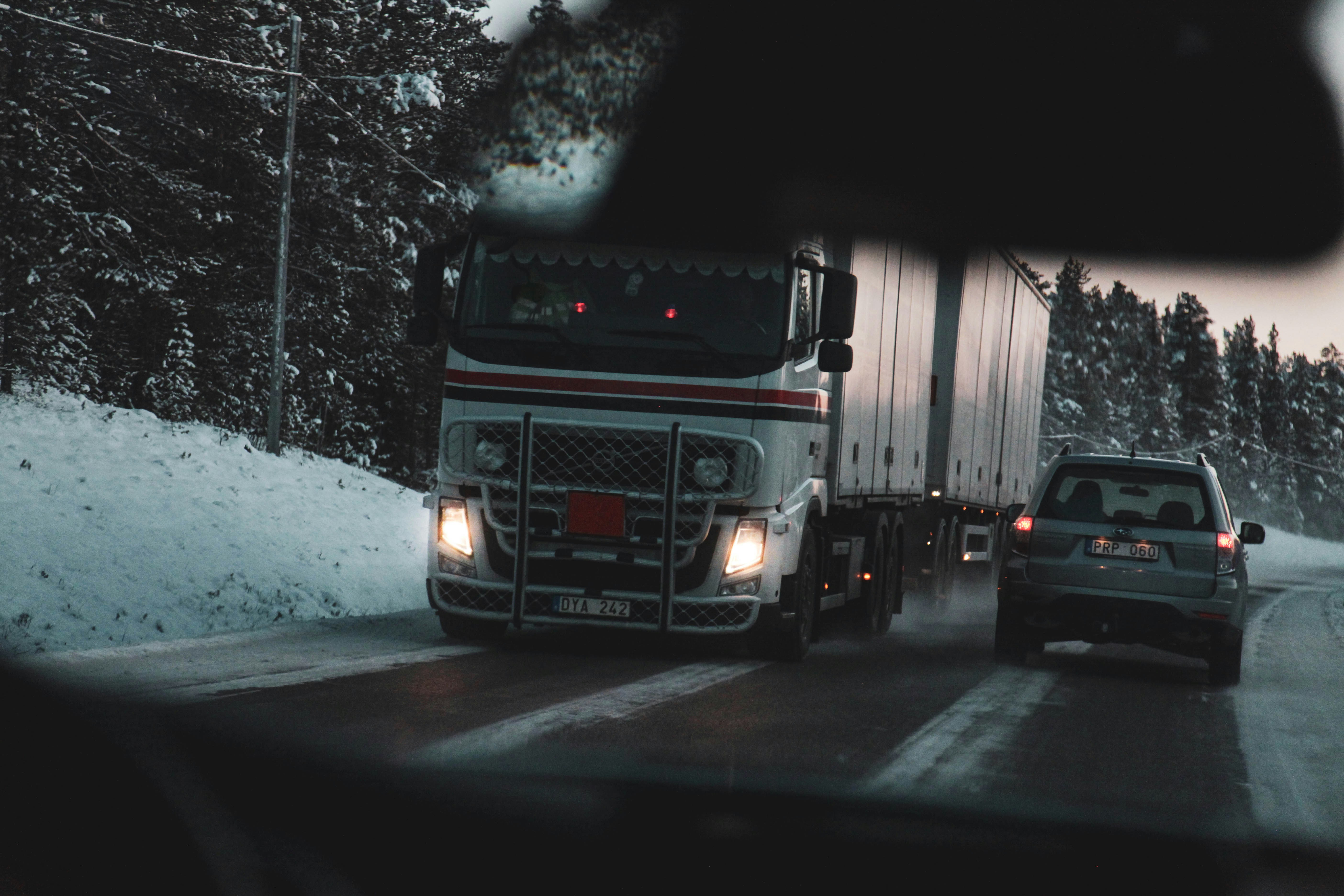 道路上の灰色の車両の近くにある白い貨物トラック