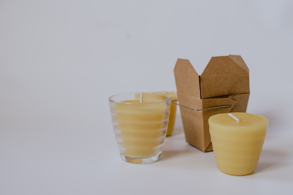 three yellow pillar candles near small brown box