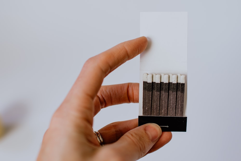 a hand holding a pack of matches on a white background