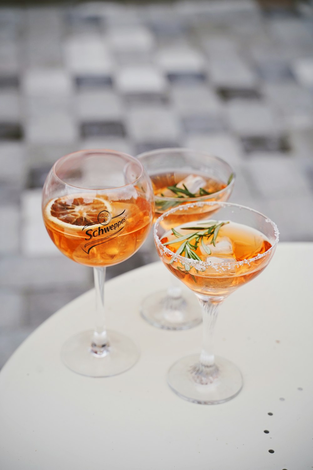 three glasses of wine with rosemary on round white table