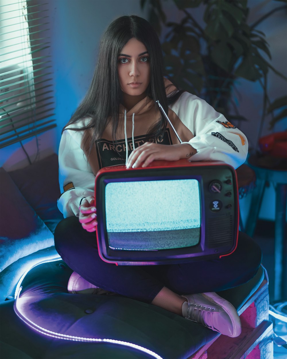 woman wearing pullover hoodie holding red CRT TV