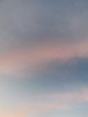 A soft gradient of pastel colors with a mix of light pink and blue hues across a clear sky.