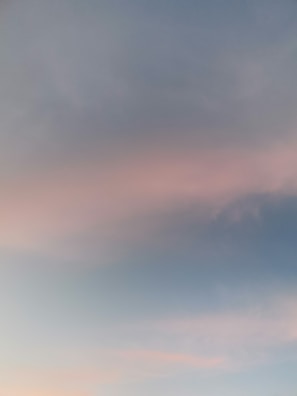 A soft gradient of pastel colors with a mix of light pink and blue hues across a clear sky.