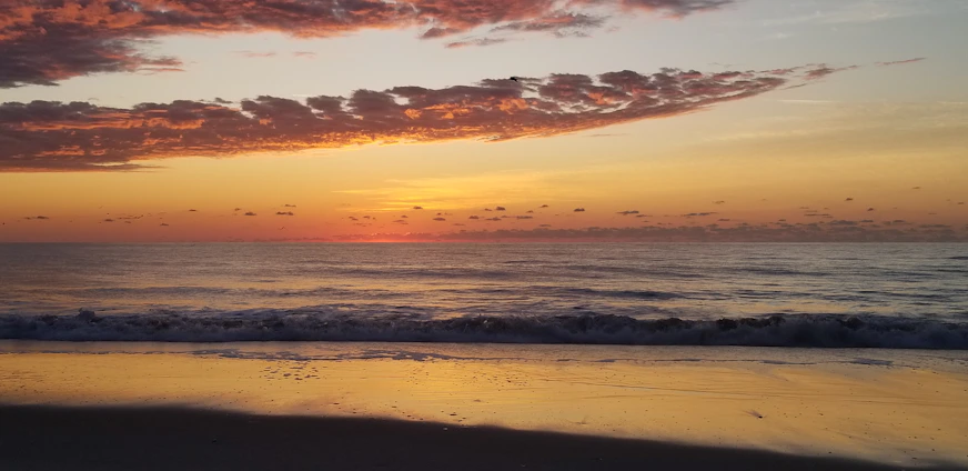 A serene drone shot capturing a peaceful sunrise over calm ocean waves