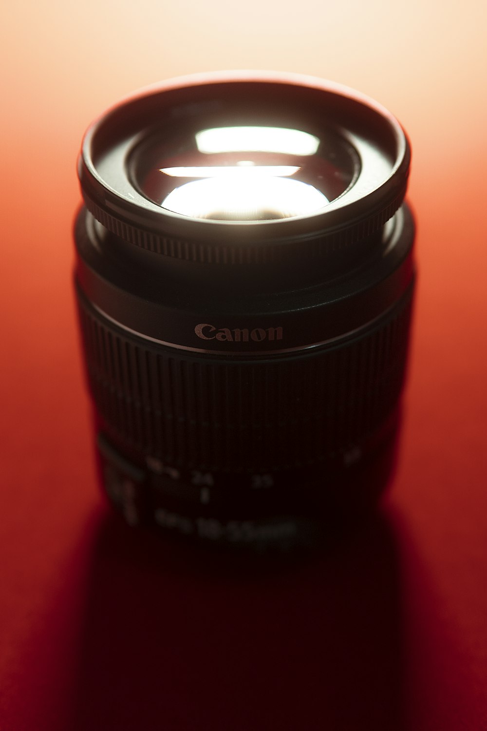 black Canon camera lens on red surface