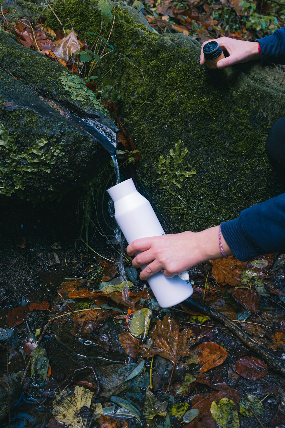 person filling the bottle with water in stone