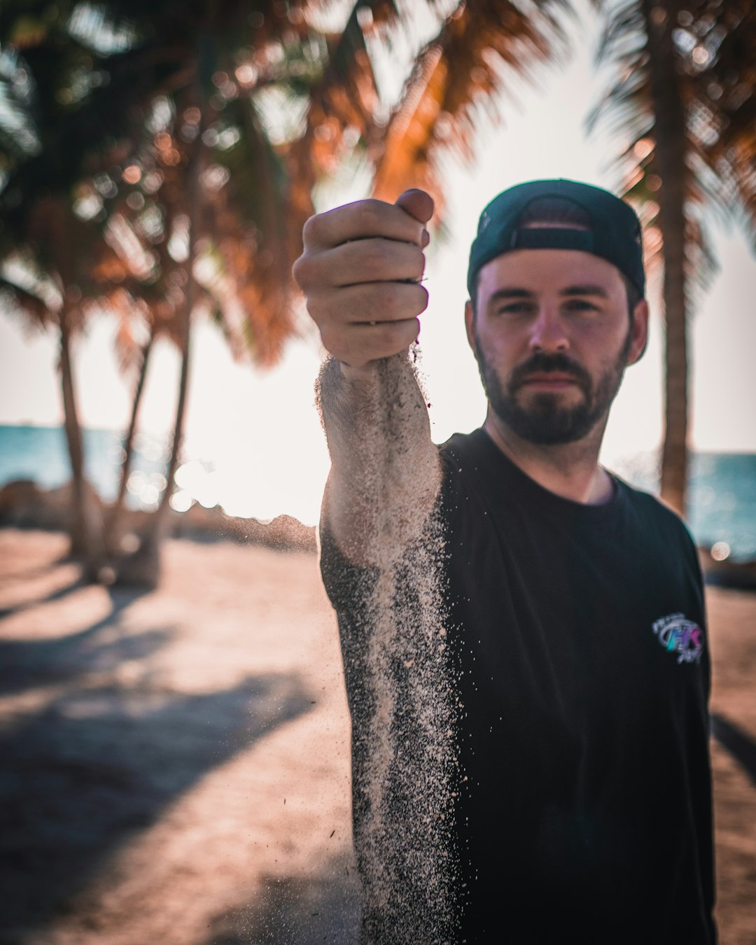 man wearing black crew-neck shirt dropping sand