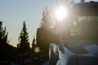 A close-up of a vehicle's untinted windows reflecting harsh sunlight on a sunny day.