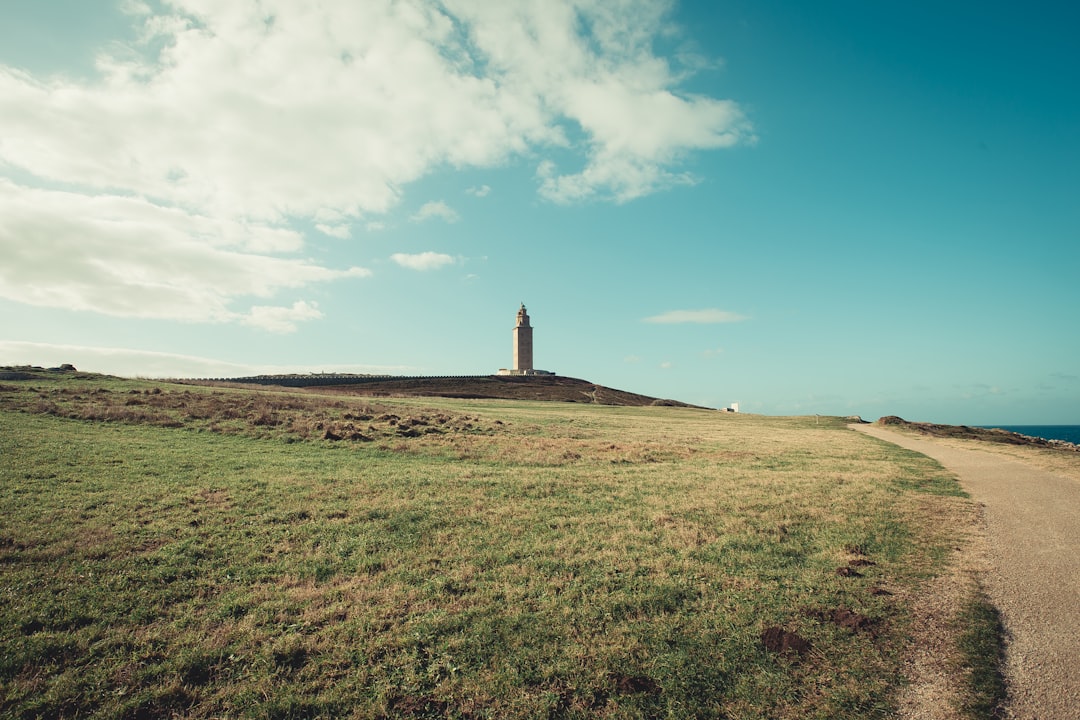 view photography of lighthouse and grass during daytime