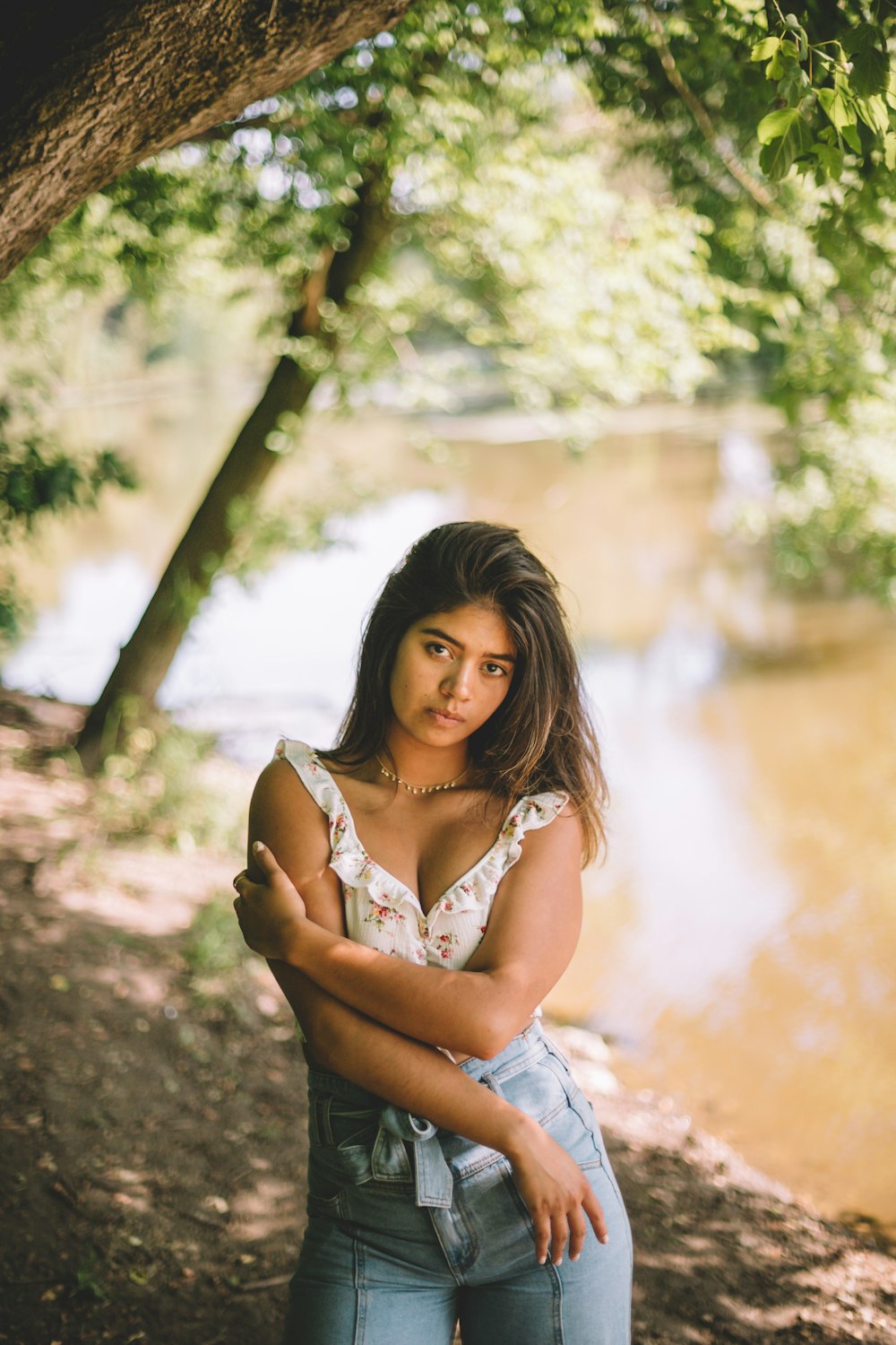 woman in white top standing beside body of water