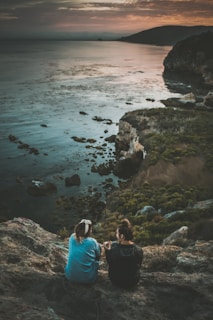 two person sitting on cliff
