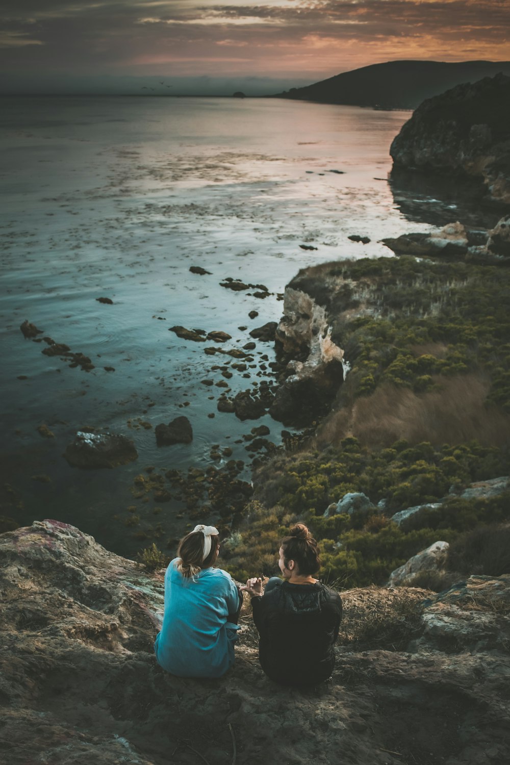 two person sitting on cliff