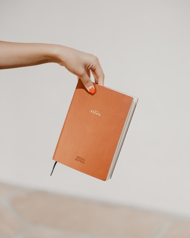 Close-up of hands holding a vintage leather-bound journal, symbolizing reflection and planning.
