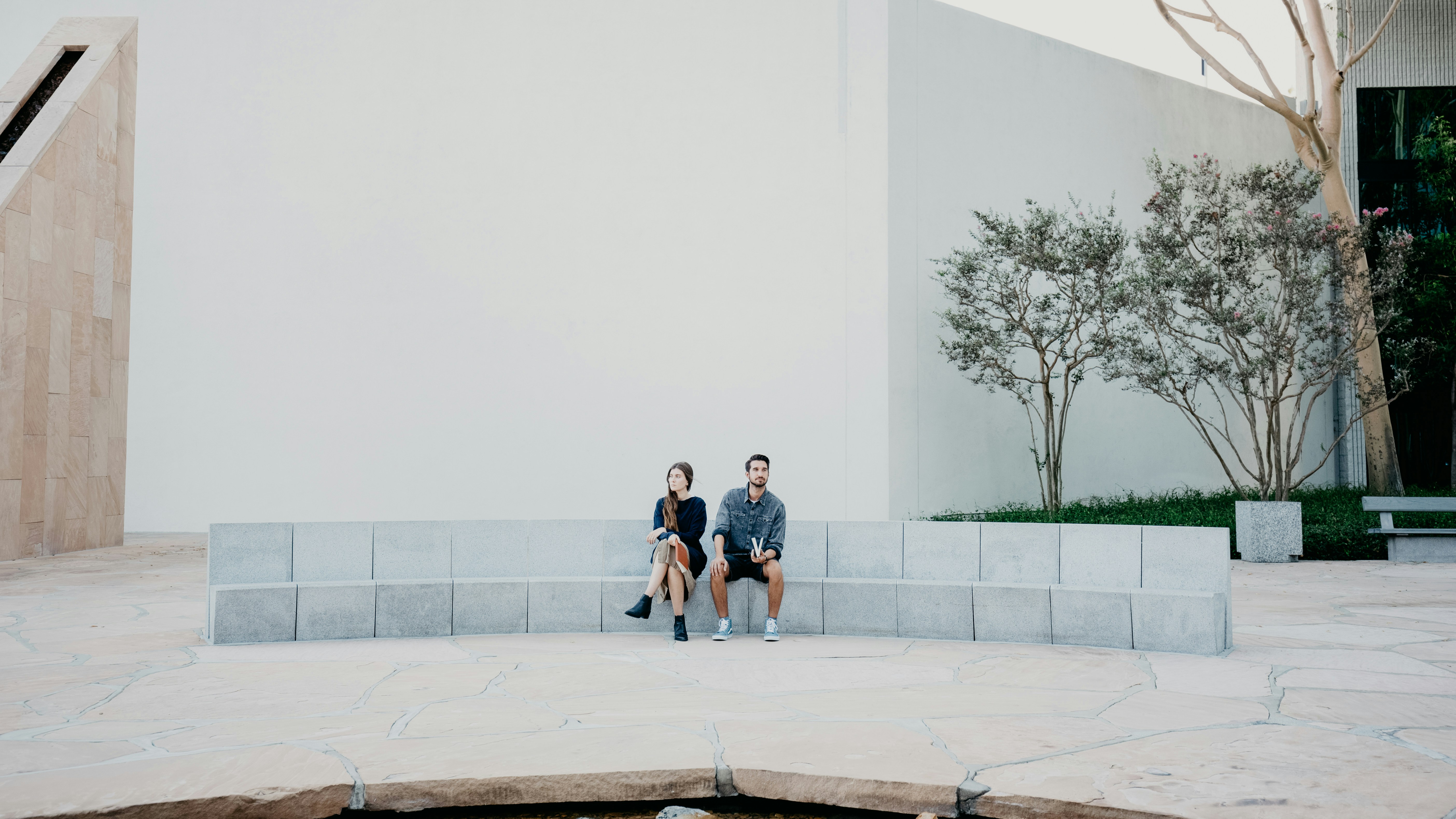 man and woman sitting on concrete bench