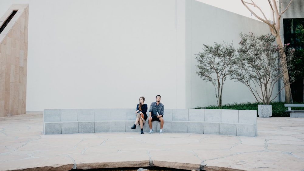 man and woman sitting on concrete bench