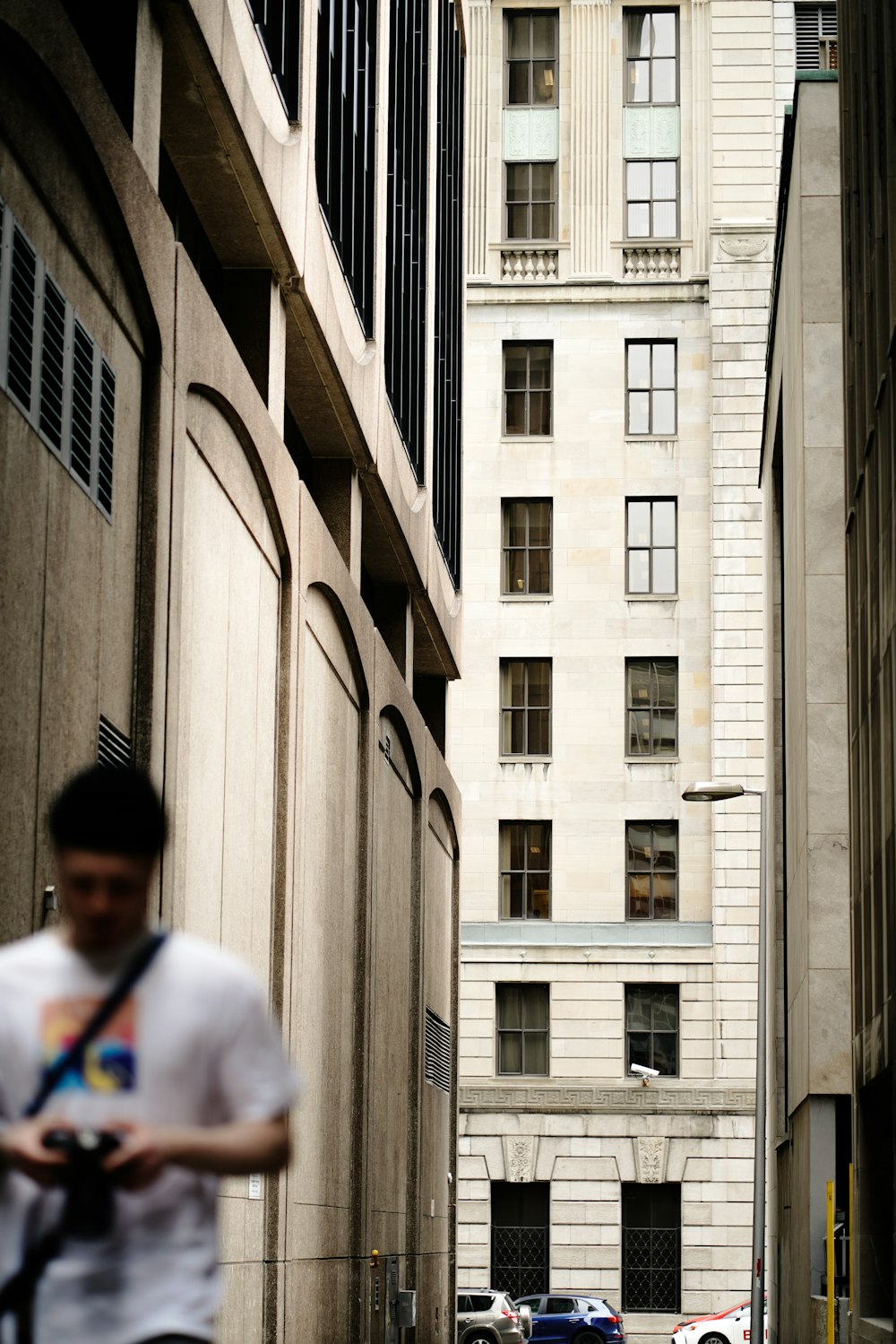man in white shirt walking beside building