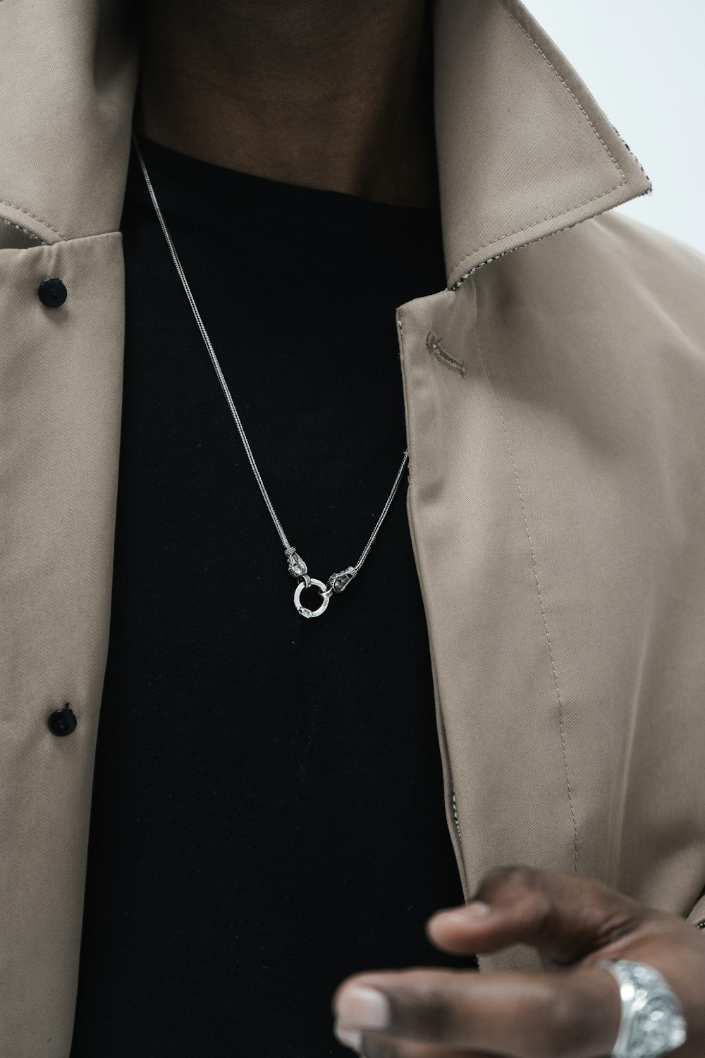 person wearing gray coat and silver-colored necklace