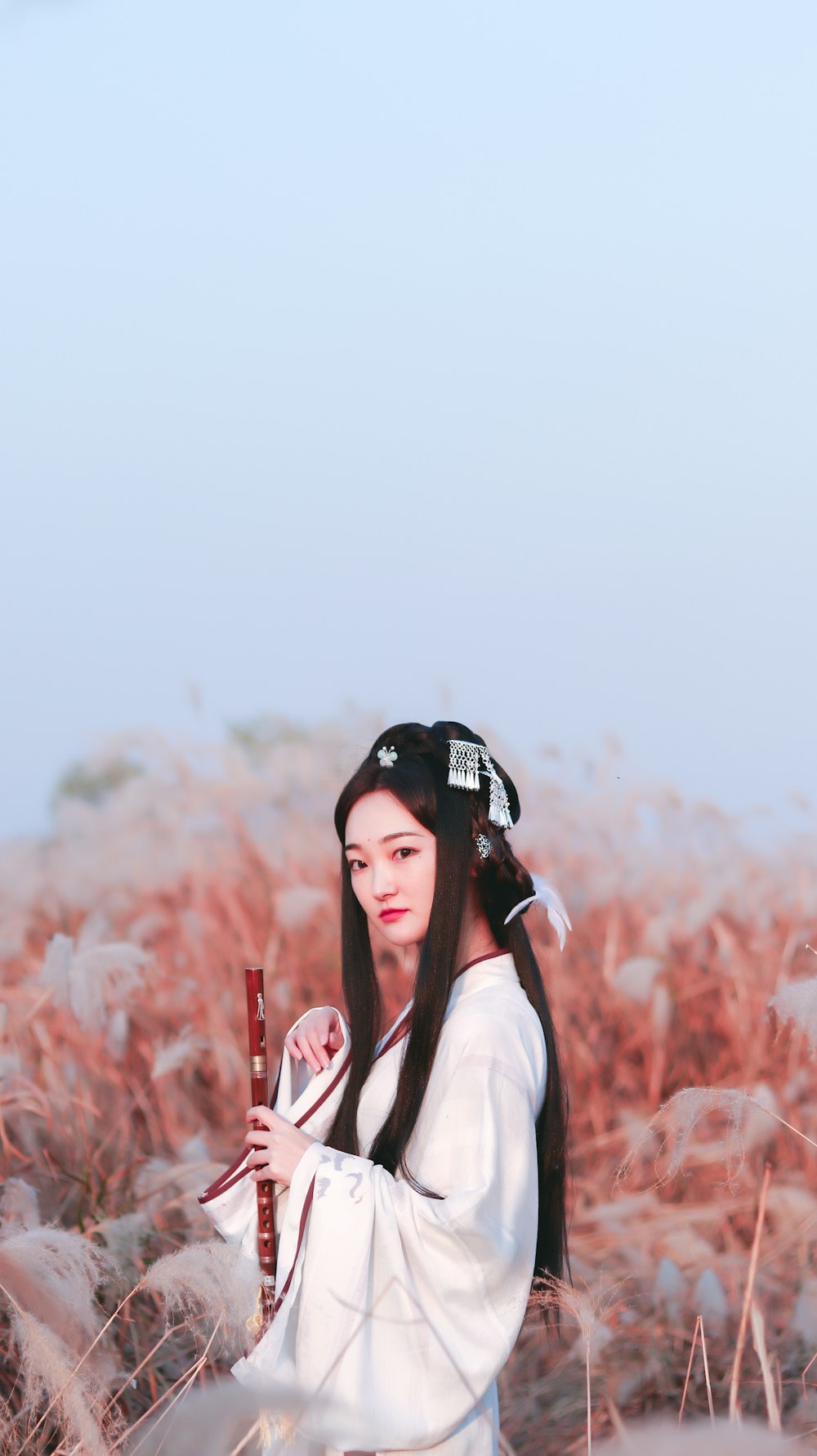 woman wearing white kimono holding red flute