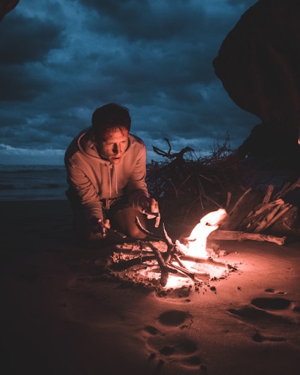 A rugged survivalist reading a weathered manual by a campfire under a starry night.