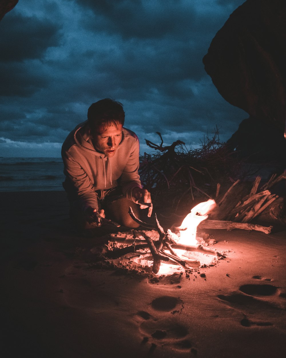 man sitting beside bonfire