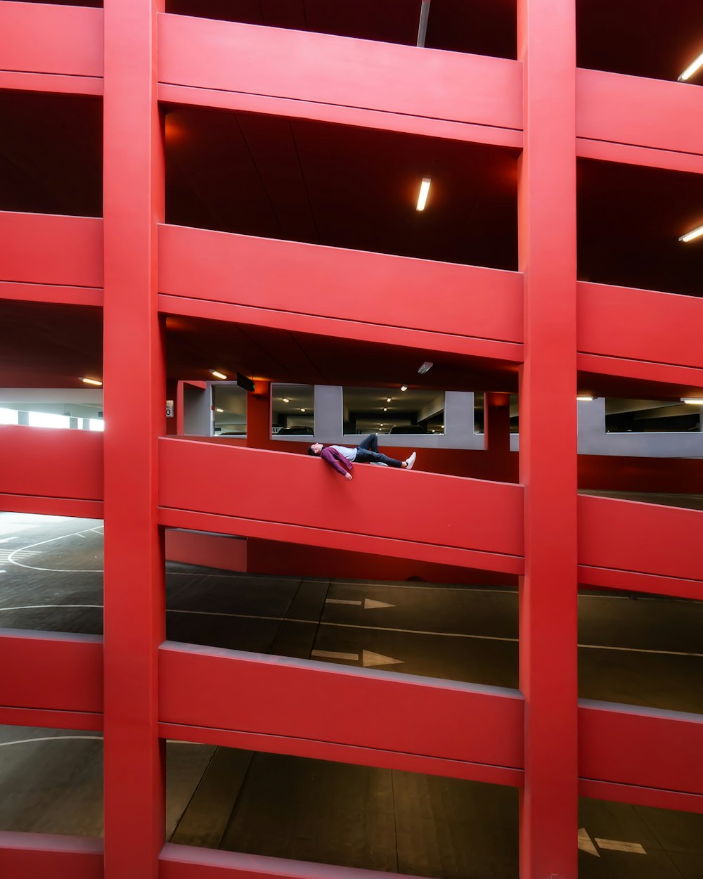 person lying on railing of parking lot building