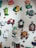 A collection of colorful, whimsical wall clocks and decorations featuring playful designs such as a cat, fish, crab, horse, teacups, and a red barn. Each piece is crafted with bold colors and imaginative shapes, creating a lively and artistic display.