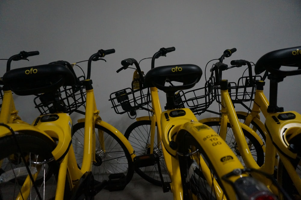 several yellow rigid bikes parked beside wall