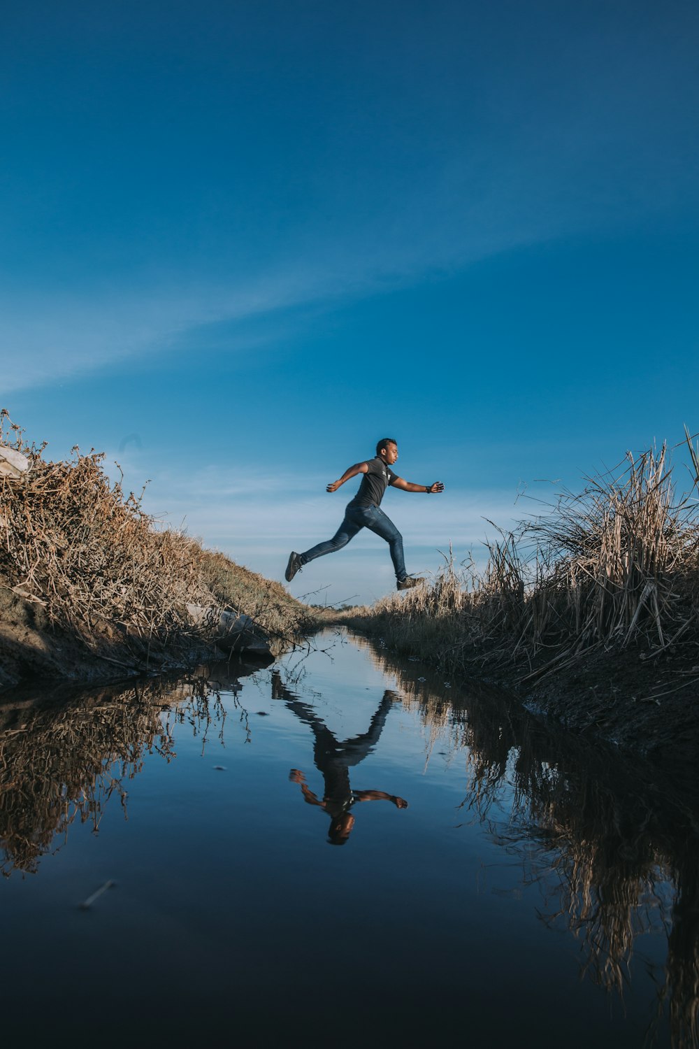 man jumping over stream