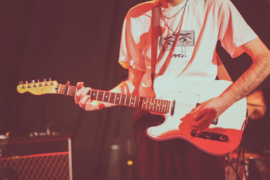 man wearing white crew-neck shirt playing electric guitar