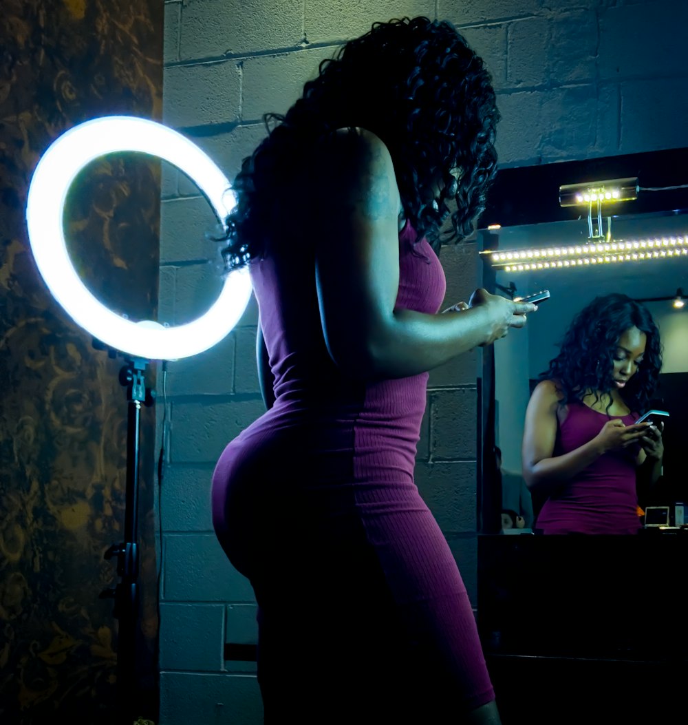 woman in maroon dress standing beside halo light