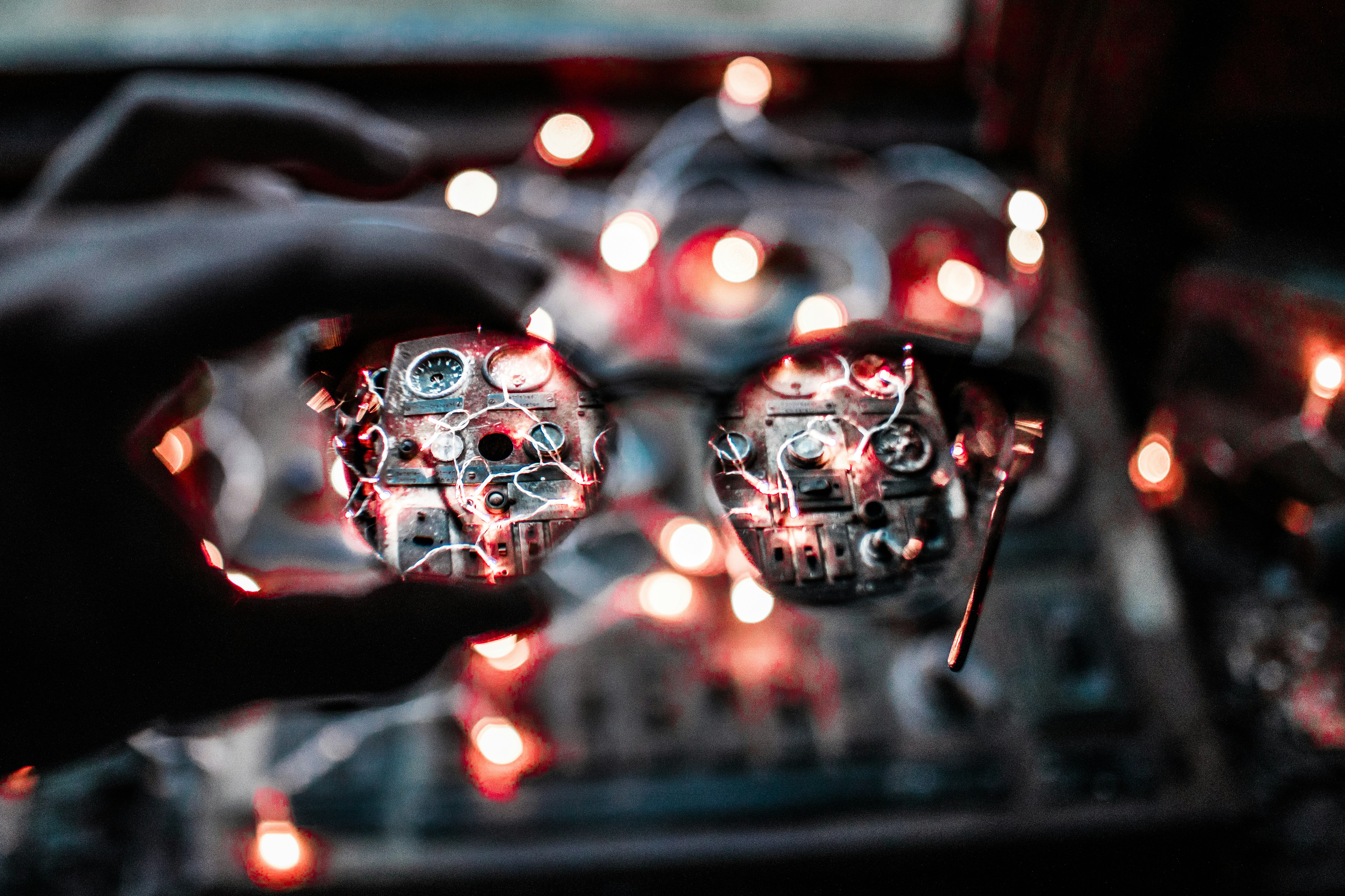 Hand holding detailed steampunk goggles with glowing lenses.