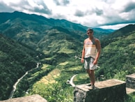A traveler standing at the edge of a lush green cliff overlooking Bali’s rice terraces.