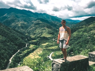 A traveler standing at the edge of a lush green cliff overlooking Bali’s rice terraces.