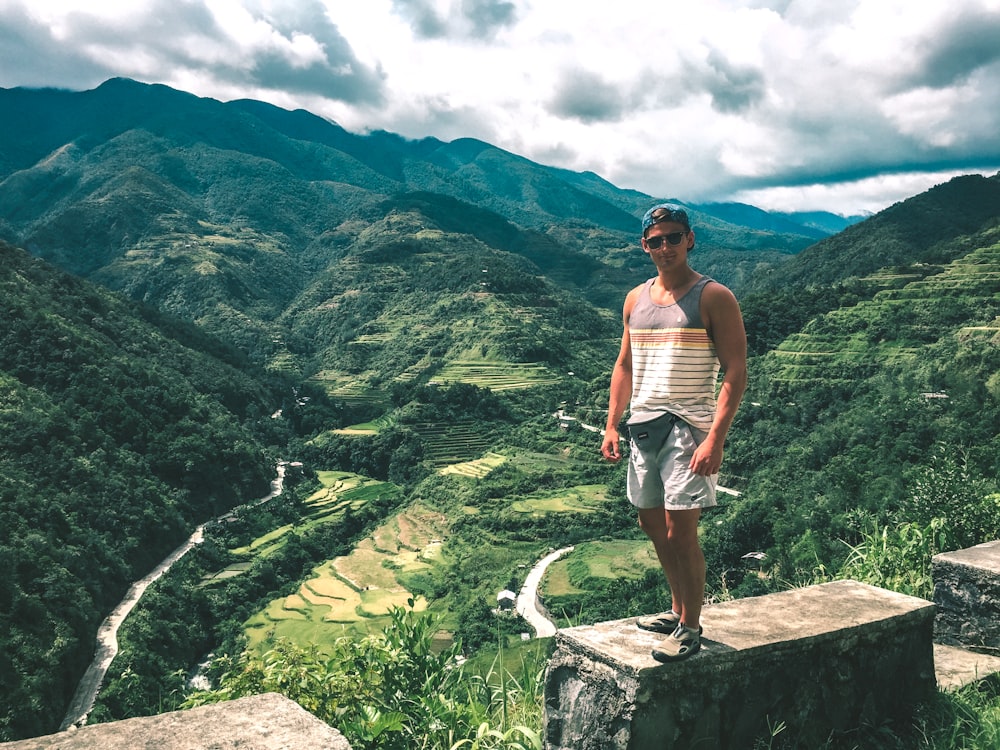 man wearing gray and white striped sleeveless shirt standing uphill during daytime